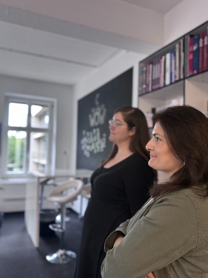 Two women in a room with books and a board.